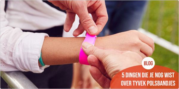 iemand brengt een roze tyvek polsbandjes aan bij een bezoeker van een outdoor event