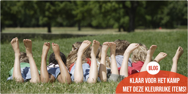 een groep kinderen ligt in het gras op een jeugdkamp met de beentjes omhoog