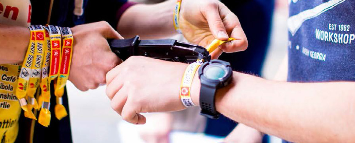 close-up van een festivalbandje dat aan de kassa om de pols gedaan wordt met een sluittang