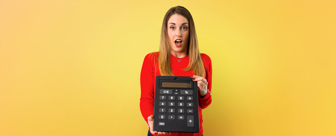 dame op een gele achtergrond met grote calculator om de kostprijs voor bedrukte kleding te berekenen