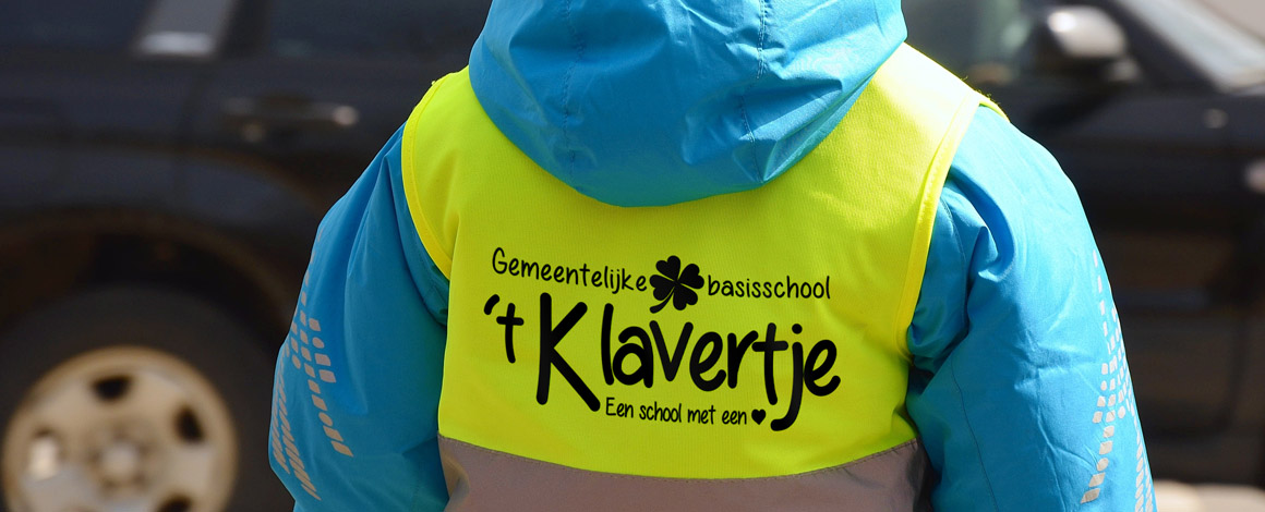kind wandelt op straat en draagt een fluohesje met bedrukking van een school
