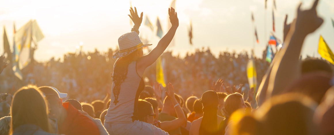 een festivalterrein met vele bezoekers terwijl de zon bijna ondergaat