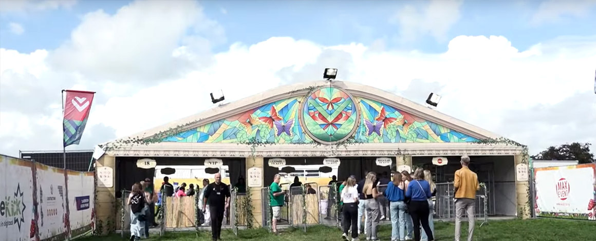 ingang van het festival Land of Love, met mooi versierde tent, bedrukte vlaggen, bordjes en spandoeken aan de inkom.