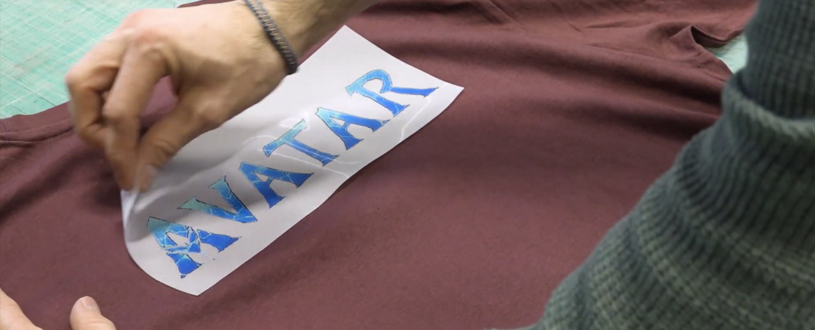 Het logo van de film Avator wordt op een rood t-shirt gedrukt bij via een transfer