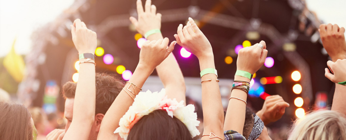 wuivende handen op een festival met de main stage op de achtergrond