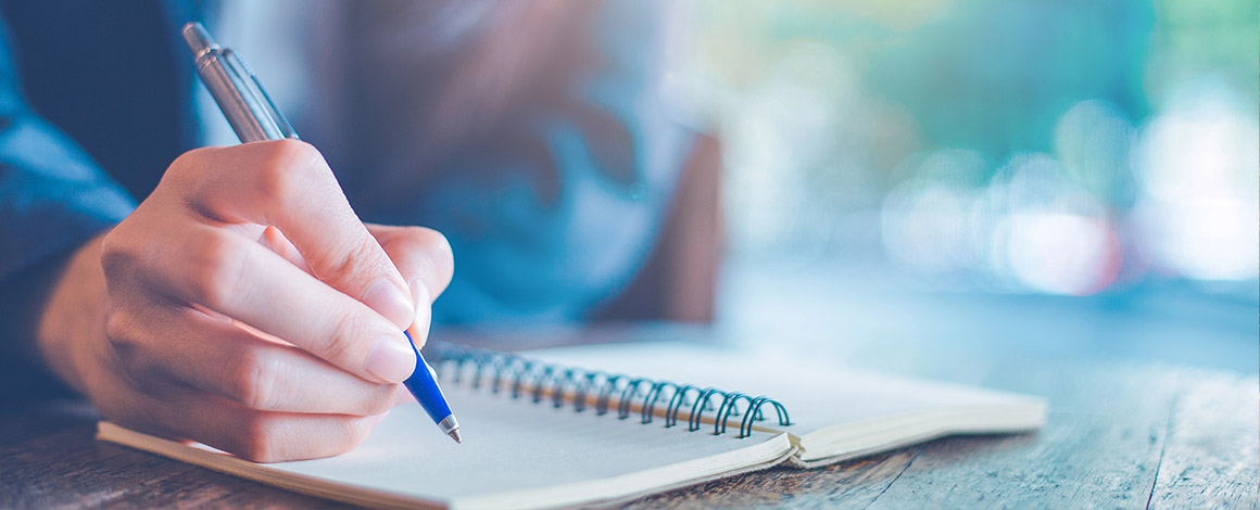 close up van bedrukte pen die aan het schrijven is op een gepersonaliseerd geringd boekje