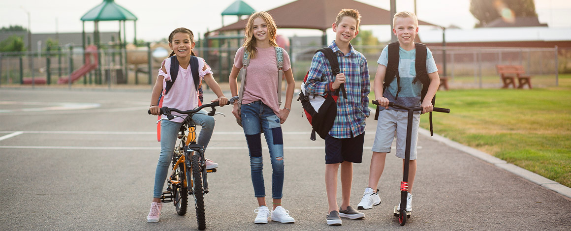 4 kinderen op straat waarvan 2 te voet, een op een fiets en een op een step, een typisch beeld tijdens Strapdag