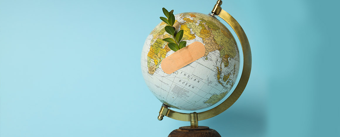 wereldbol met pleister en takje tegen blauwe achtergrond