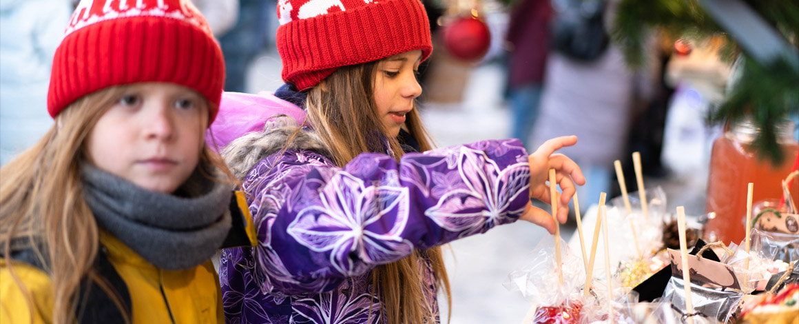 2 meisjes die op een wintermarkt rondlopen en nieuwsgierig alle versiering bekijken